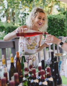 a person in a garment standing next to a table full of bottles