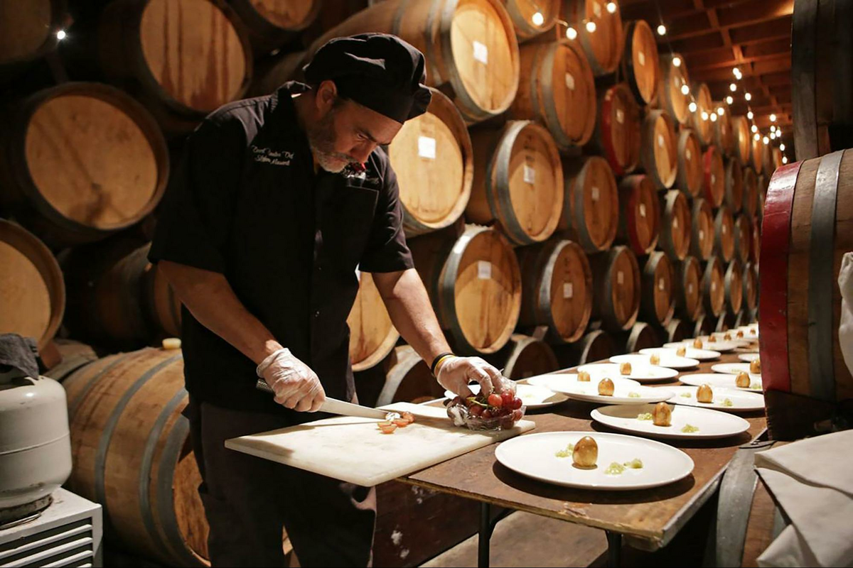 a man in a wine cellar cutting food on a cutting board